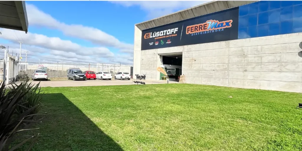 Ferremax Distribuidora: experiencia, respaldo y crecimiento 1 Frente e ingreso de Ferremax con vista de parque y estacionamiento